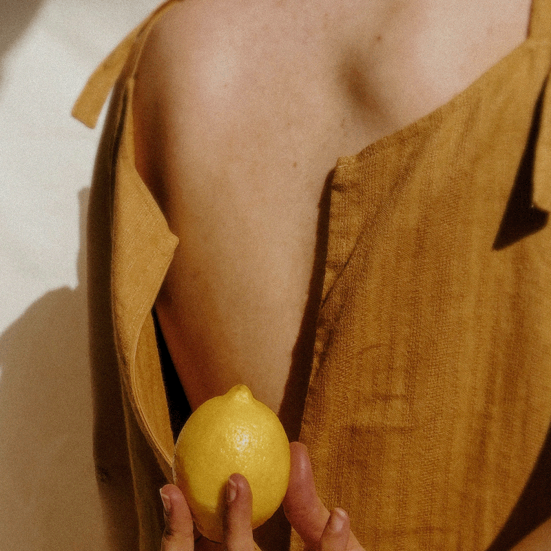 Hand holding lemon against bare shoulder