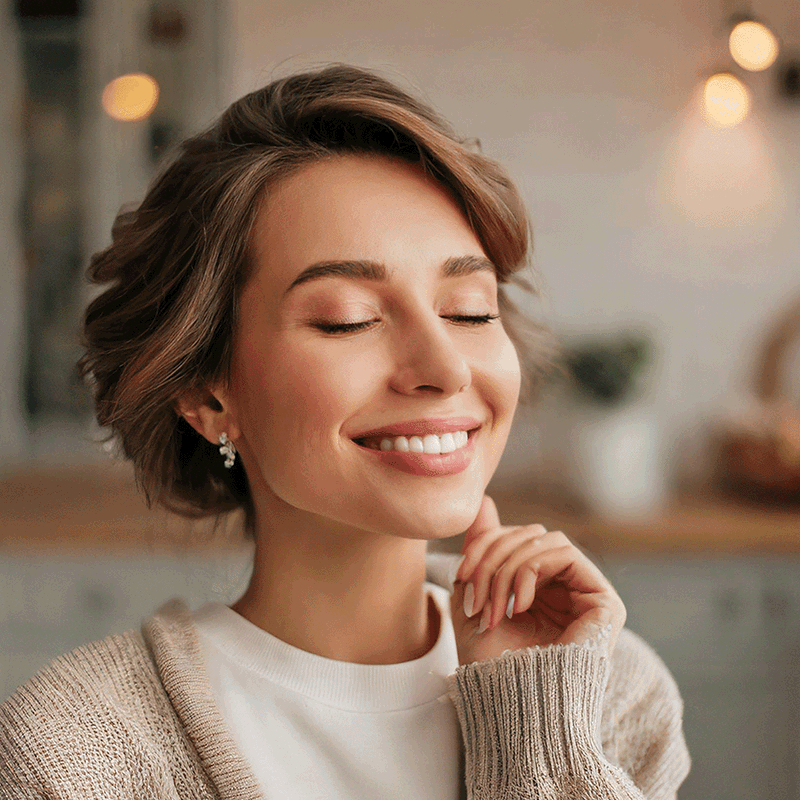 Smiling woman with eyes closed in cozy indoor setting
