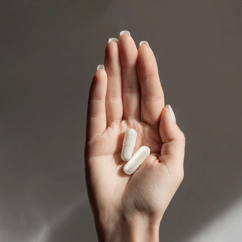 Hand holding two probiotic capsules