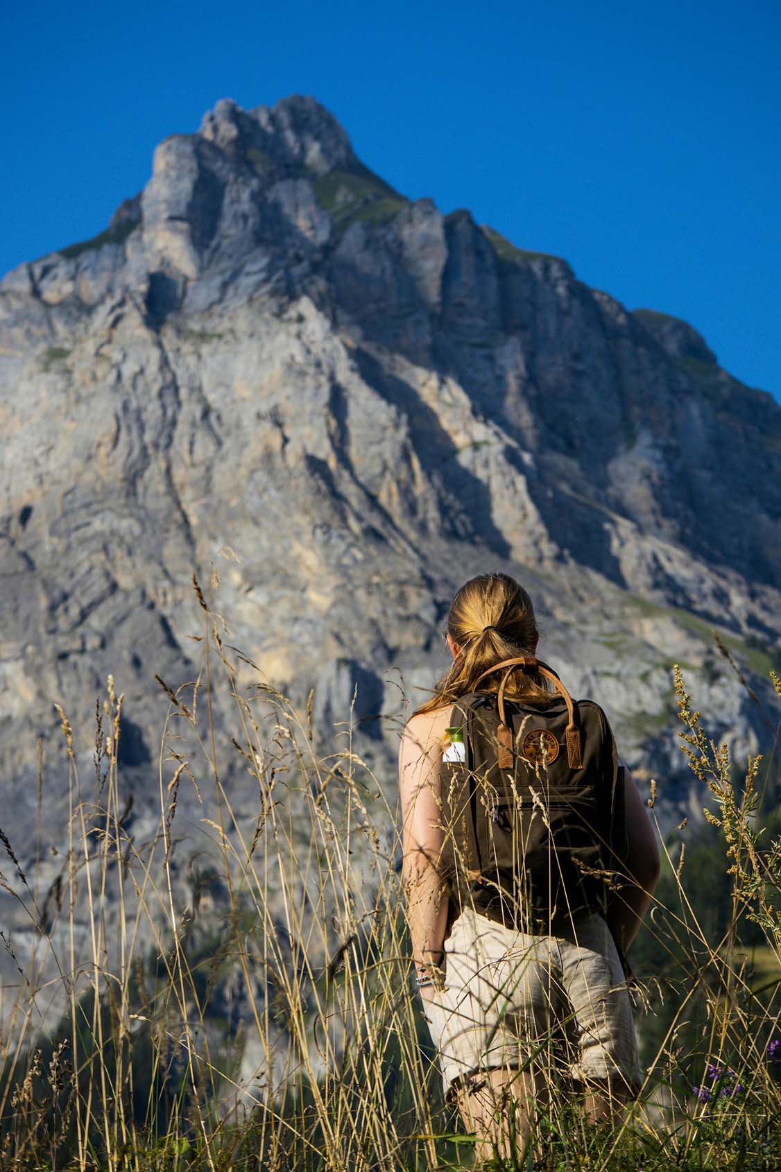 Woman with backpack looking at mountain cliff